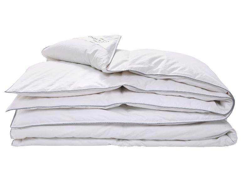 Wit dekbed en kussen met grijze bies, opgevouwen en gestapeld.