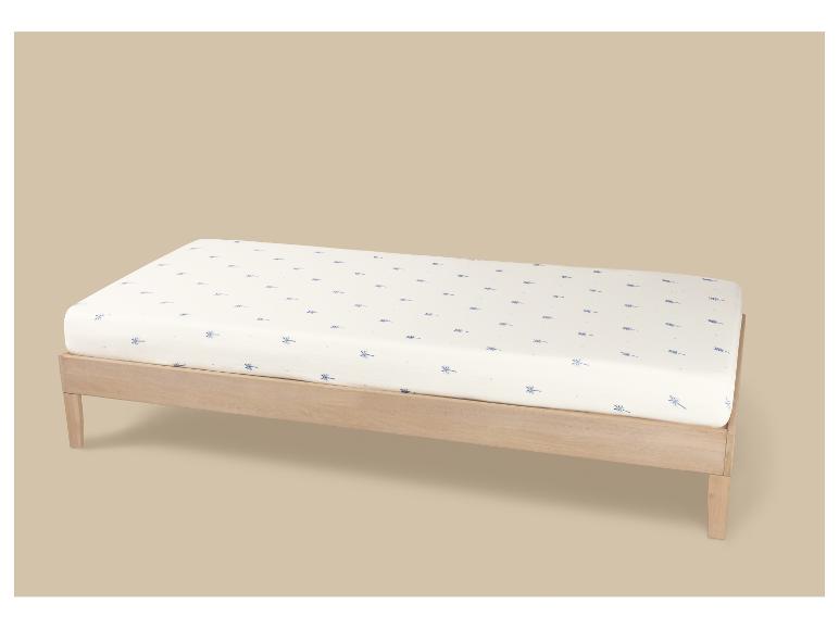 Houten eenpersoonsbed met een wit matras met een blauw libellenpatroon.