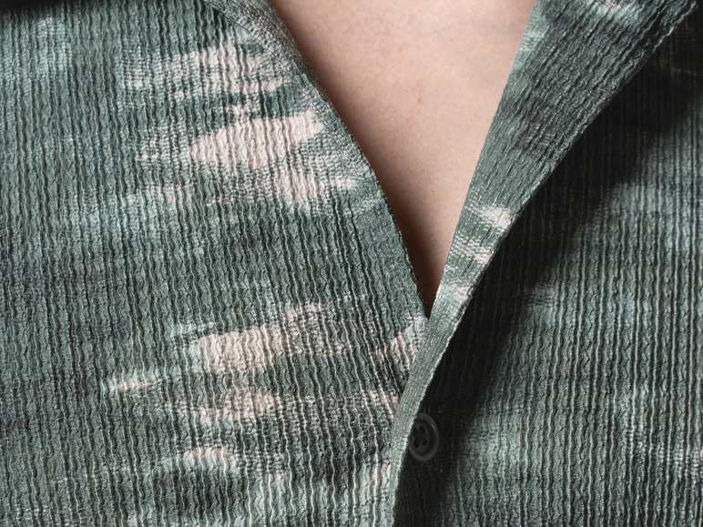 Close-up van een groene gebloemde overhemd met knoop.