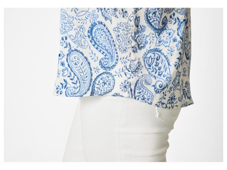 Witte blouse met blauw paisley-patroon en witte broek.
