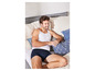 Man in witte tanktop en blauwe onderbroek liggend op bed.