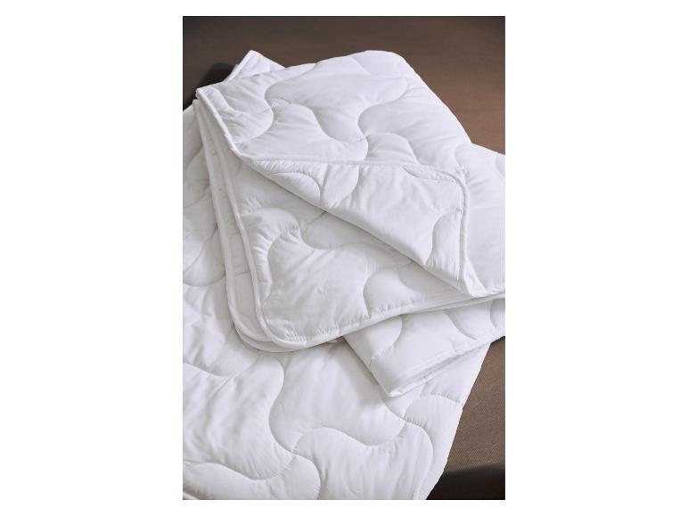 Wit gewatteerd dekbed of deken opgevouwen op een bruine ondergrond