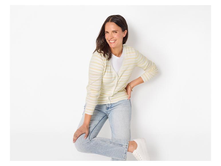 Lachende vrouw in gestreept vest, wit T-shirt en jeans.