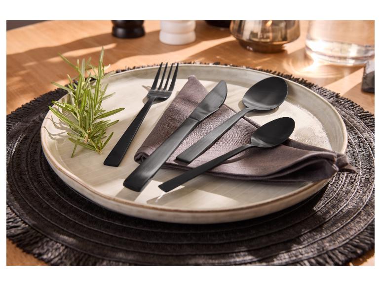 Zwart bestekset op een bord met servet en rozemarijntakje, op een donkere placemat.