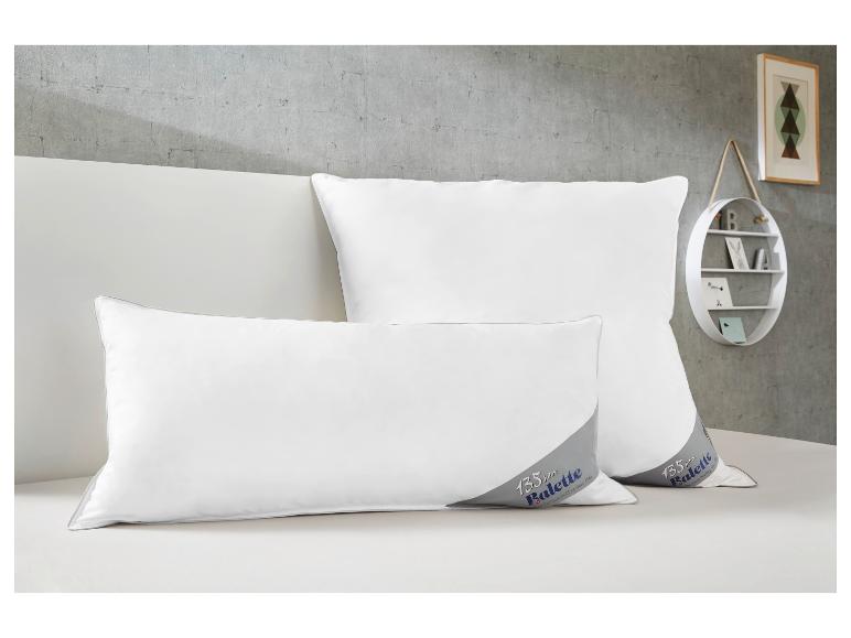 Twee witte Balette kussens met 135-jarig jubileumlogo op een bed.