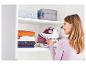 Vrouw die een Tefal strijkijzer en kleding in een kast opbergt.