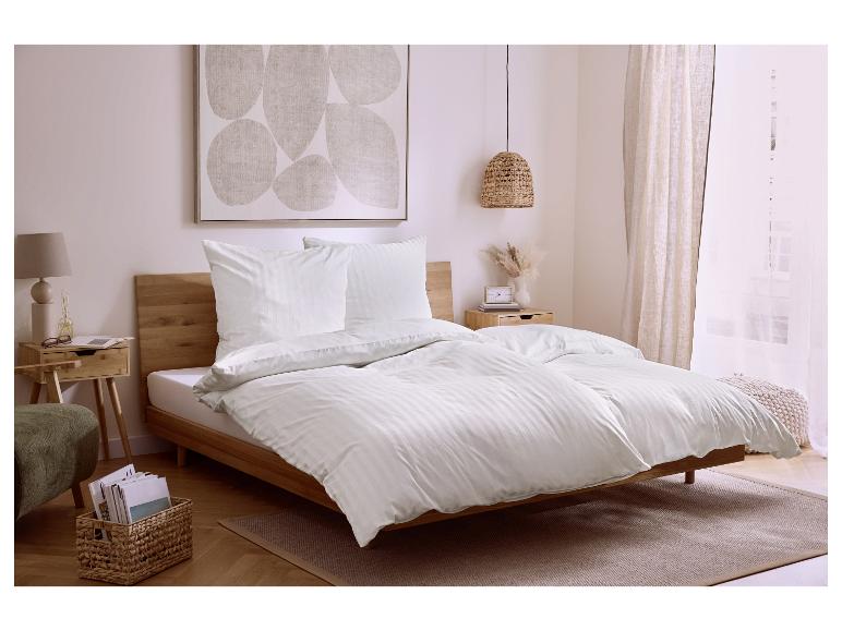Slaapkamer met wit gestreept beddengoed, houten meubels en moderne kunst.