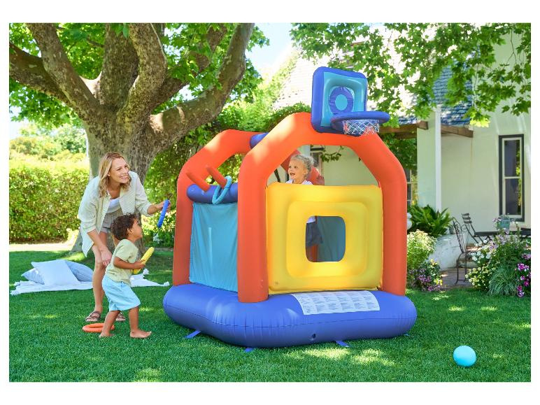 Opblaasbaar kasteel met basketbalring, kinderen spelen in de tuin.
