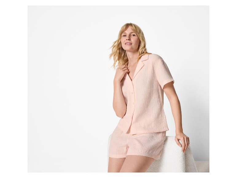 Vrouw in perzikkleurige pyjama met overhemd met korte mouwen en korte broek.