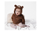 Schattig baby in een bruine teddyberen jumpsuit.