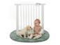 Baby en puppy spelen op een groen rond vloerkleed met een wit veiligheidshekje.