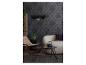 Woonkamer met donker patroonbehang, zwarte hanglamp, beige fauteuil en bank, en een kleine tafel.