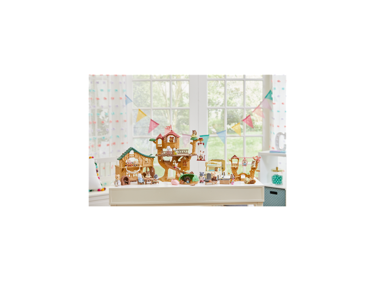 Kinderspeelset met boomhut, dierenfiguren en camper op een witte tafel.