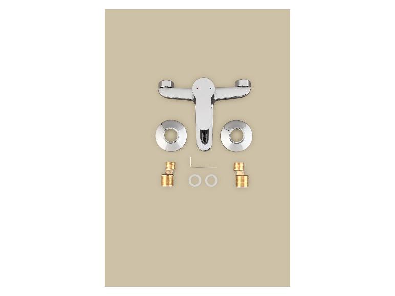 Verchroomde kraan met installatieonderdelen op een beige achtergrond.
