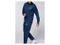 Man in marineblauw trainingspak met groen en blauw logo, witte sneakers.