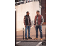 Twee mannen in geruite overhemden, jeans en gewatteerde bodywarmers staan buiten.