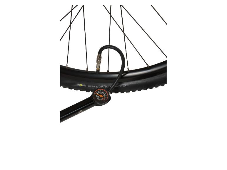 Fietspomp met manometer aangesloten op een zwarte fietsband.