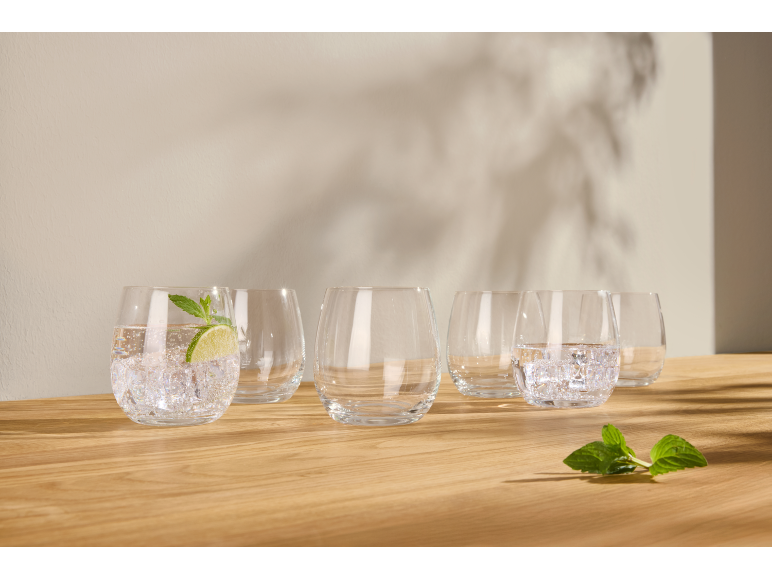 Glazen met water, ijs, limoen en munt op een houten oppervlak.