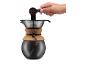 Hand giet gemalen koffie in een pour-over koffiezetapparaat met kurken band.