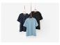 Drie eenvoudige t-shirts in verschillende kleuren hangen aan hangers.