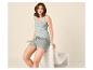 Lachende vrouw in lichtgroene tanktop en short, zittend op een stoel.