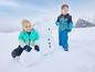 Twee kinderen in winterkleding maken een sneeuwpop.