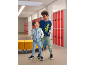 Twee jongens in een schoolgang die bijpassende baseballjacks en joggingbroeken dragen.