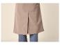 Onderkant van een beige jas of mantel met een split aan de achterkant, over een blauwe jeans.