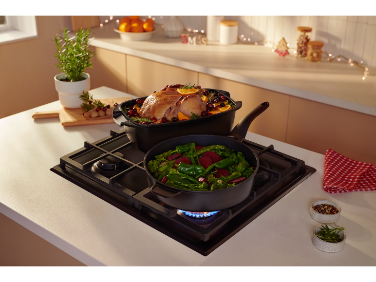 Gebraden kip en groenten die koken op een gaskookplaat in kerstsfeer.
