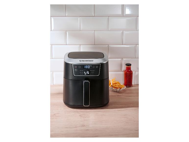 Zwarte SilverCrest airfryer met friet en saus op een houten aanrecht.