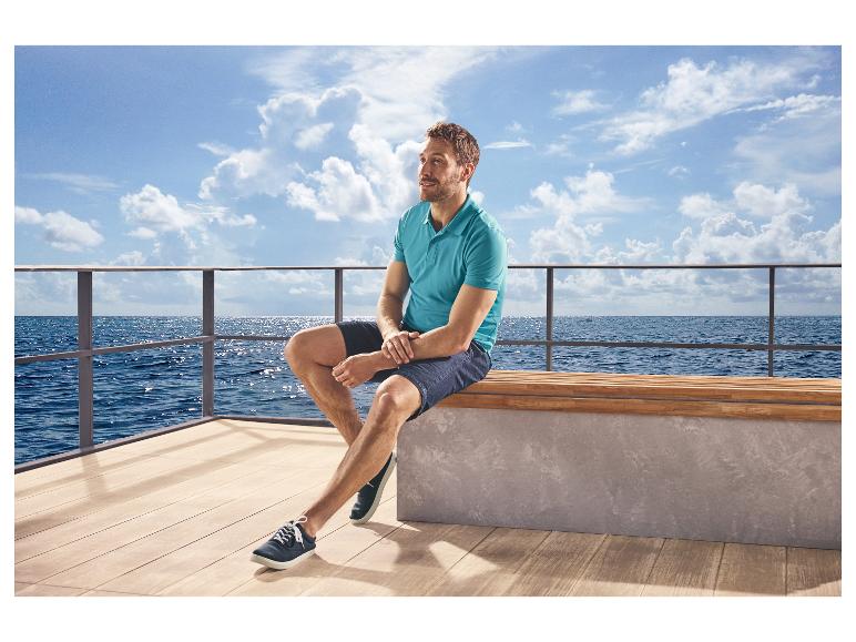 Man in lichtblauw ESMARA MEN piqué poloshirt en korte broek, zittend op het dek van een boot.
