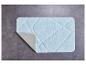 Een lichtblauw badmat met een ruitpatroon op een grijze tegelvloer.