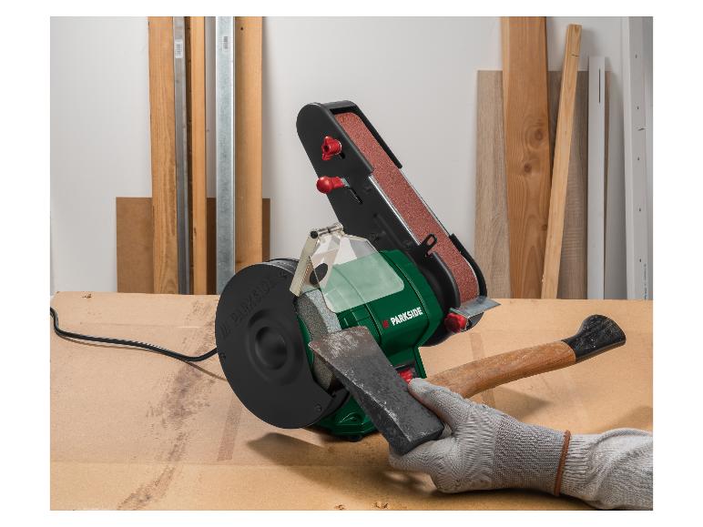 Band- en schuurschijf voor het slijpen van een bijl op een houten tafel.
