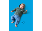Baby in groen vest met capuchon en blauwe broek, met een blauwe rammelaar.