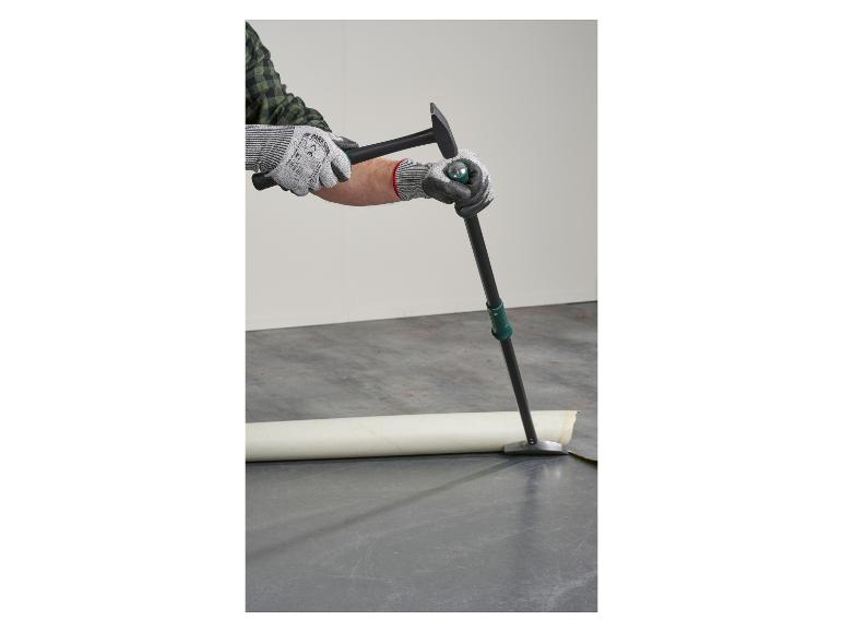 Een arbeider verwijdert de vloerbedekking met Parkside gereedschap.