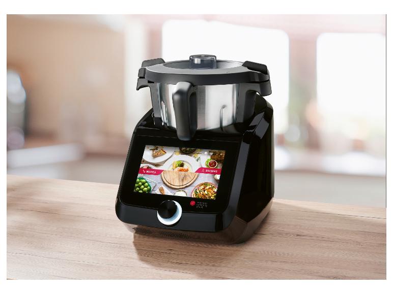 Zwarte keukenmachine met touchscreen dat modi en recepten toont, op een houten aanrecht.