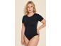 Vrouw in een zwart bodysuit met korte mouwen, hand in de zij, kijkt in de camera.
