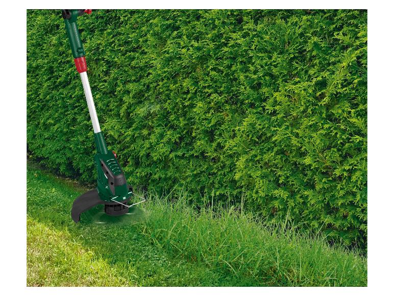 Grastrimmer maait hoog gras langs een heg.