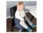 Baby in een draagbare zitverhoger op een eetkamerstoel naast een witte tafel.