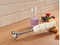 Crèmekleurige staafmixer met smoothie, bessen en snijplank op een houten aanrecht.