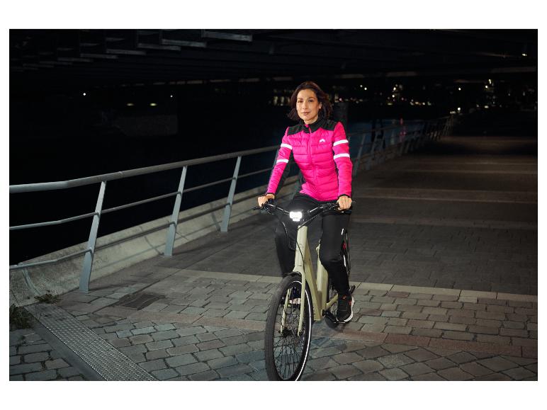 Vrouw in roze fietsjack rijdt 's nachts op een elektrische fiets.