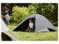 Man met kampeertas en vrouw in tent op grasrijke camping.