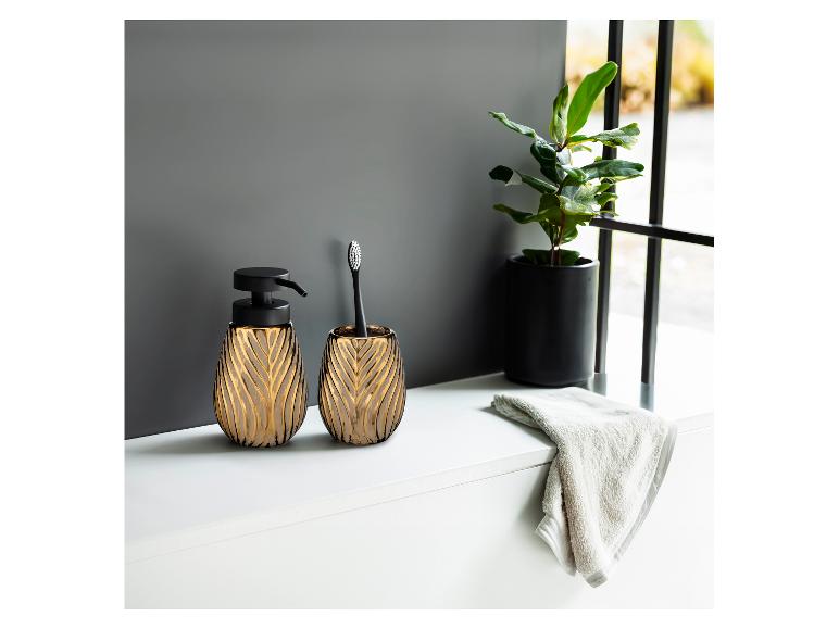 Moderne, elegante zeepdispenser en tandenborstelhouder in goud en zwart.