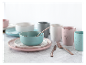 Pastelkleurige kommen en borden, mokken en rose gold bestek.