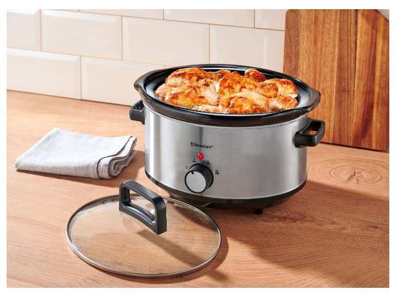 Slowcooker met kip op een houten aanrecht in de keuken.