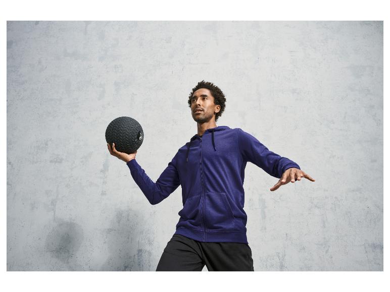 Man in een blauwe hoodie met capuchon houdt een trainingsbal vast.
