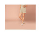 Vrouw draagt beige shorts en witte slippers.