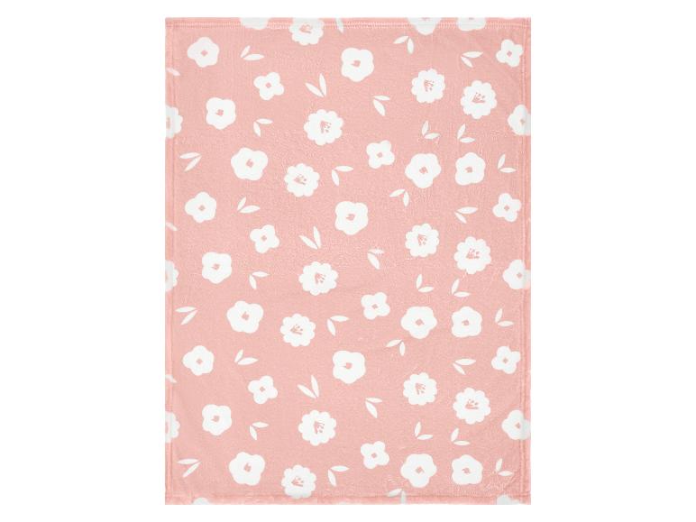 Roze deken met een patroon van witte bloemen en bladeren.
