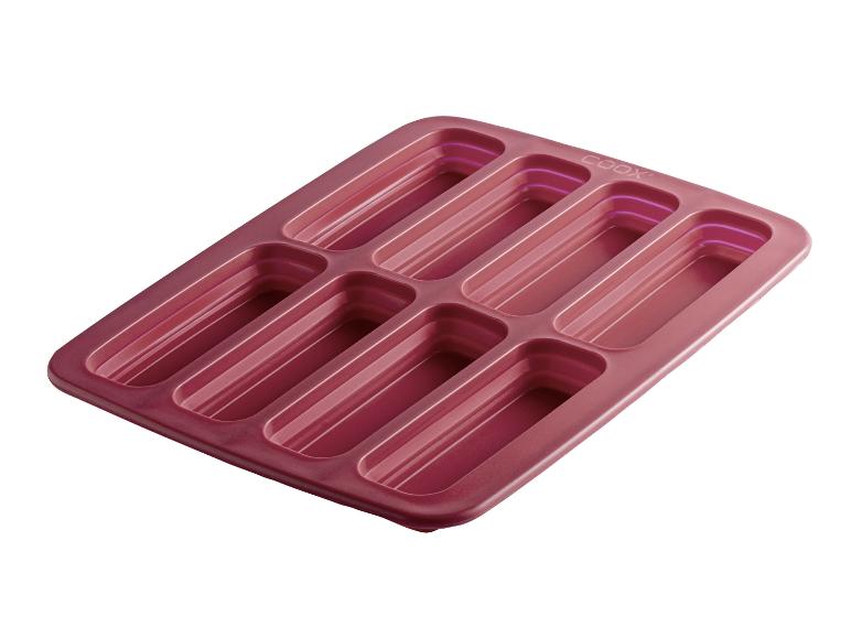 Rode siliconen bakvorm met acht rechthoekige holtes voor financiers of minicakes.