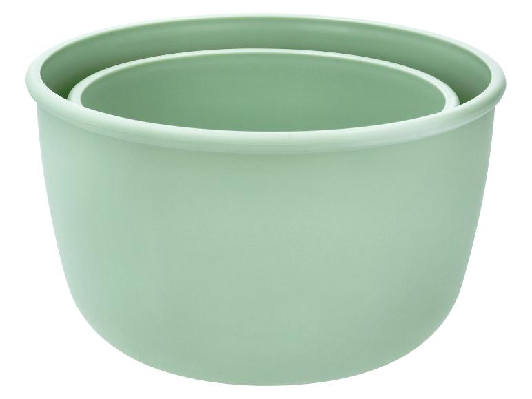 Twee groene plastic bloempotten, in elkaar gestapeld.